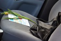 Kwiatek i ulotka na siedzeniu pasażera, obok damska torebka