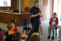 Policjant prezentuje dzieciom odznakę policyjną