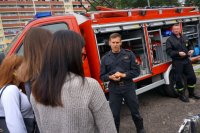 Strażak rozmawia z uczniami przy wozie strażackim