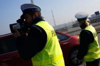 Policjant mierzy prędkość pojazdów, obok stoi policjantka